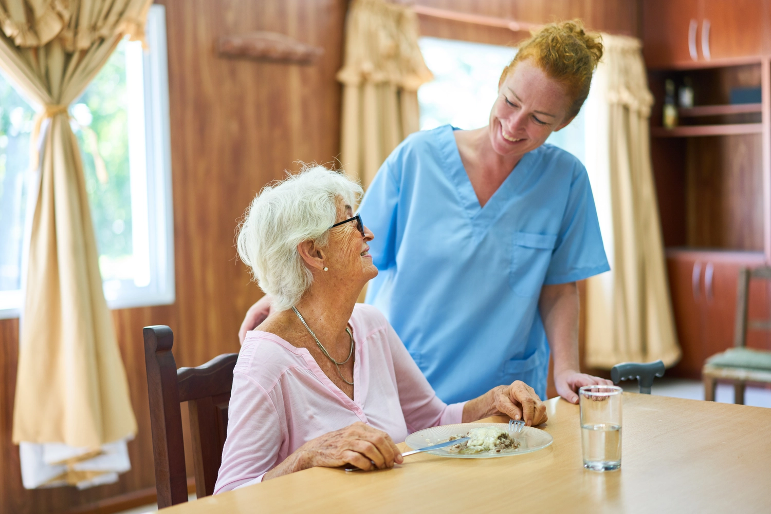 Praxis Grunewald - Physiotherapie - Pflegerin betreut Seniorin beim Mittagessen